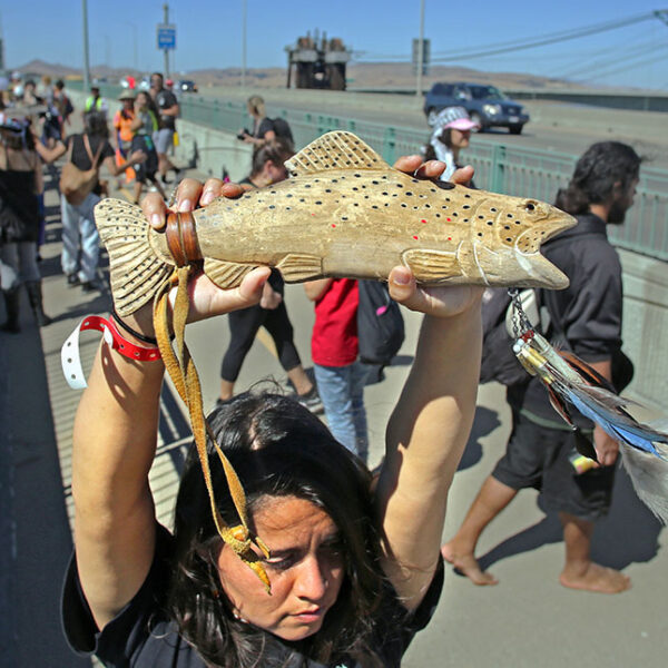 Carquinez Strait, CA — Desirae Harp (Mishewal OnastaTis Nation) holds up a wooden salmon figurine as the Run4Salmon crosses over the Benicia-Martinez Bridge. September 17, 2018. Tom Levy/The Spiritual Edge